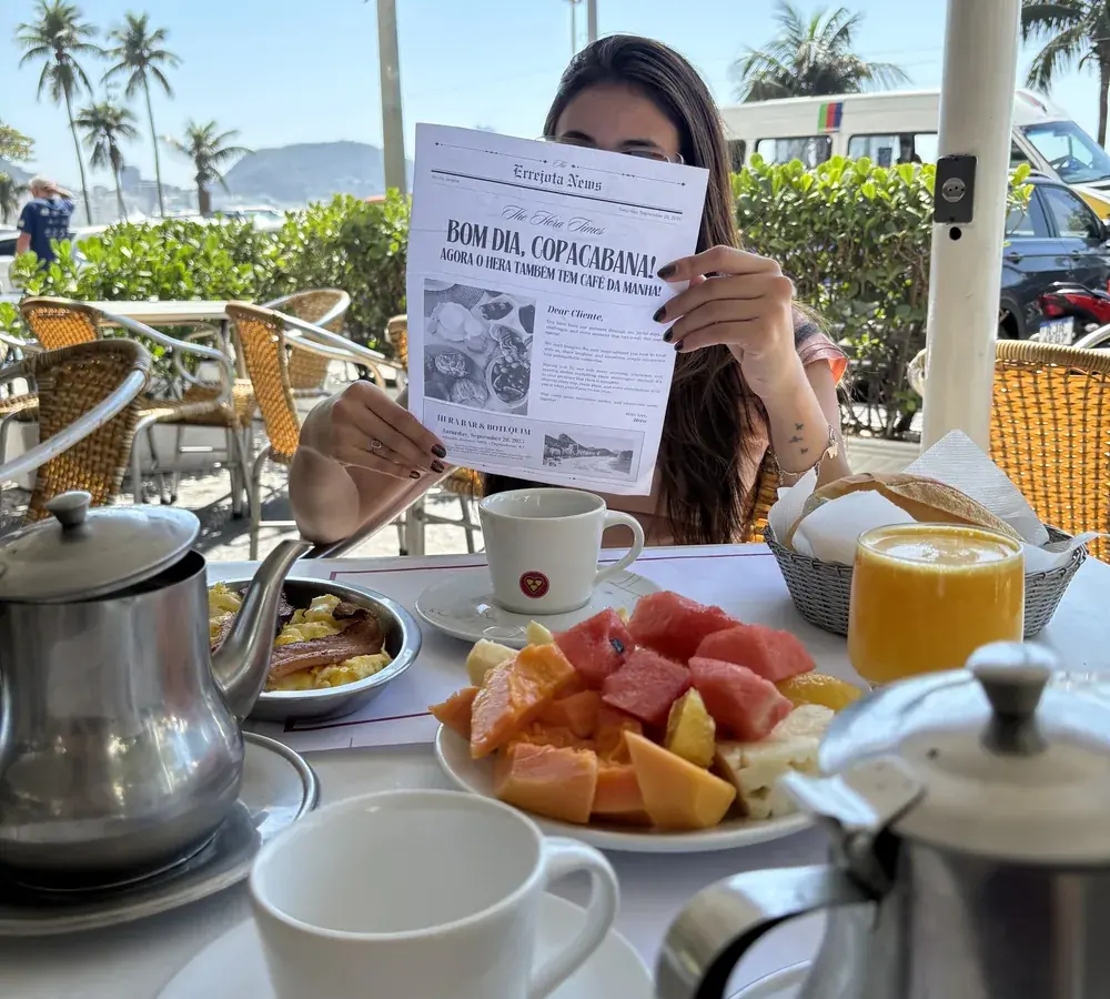 Mesa de café da manhã do Hera com bule, frutas da estação e suco, na calçada