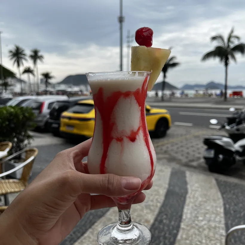 Drink servido no Hera com a orla de Copacabana ao fundo