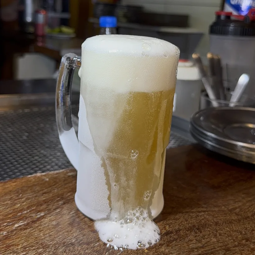 Chope transbordando de espuma servido em caneca